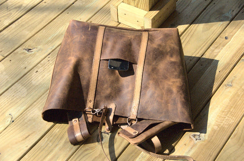 Wanderer shoulder bag laying on decking with top opening toward you. Matching accessories are seen in the top opening. 
