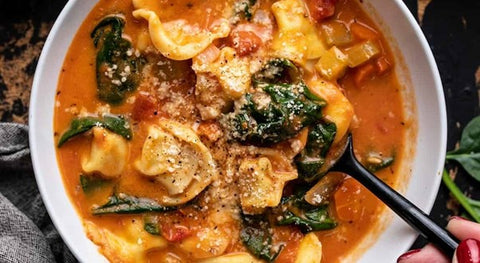 white bowl with tortellini, spinach and delicious sauce