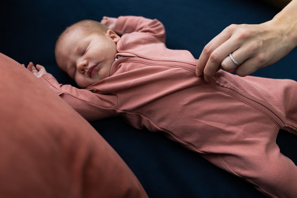 Newborn baby wears plain coloured onesie with zip and scratch mitts