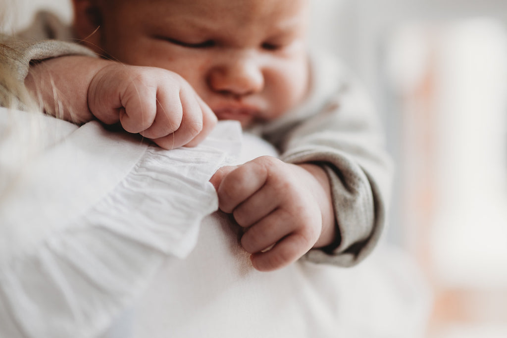 Newborn baby boy wears organic cotton onesie in grey