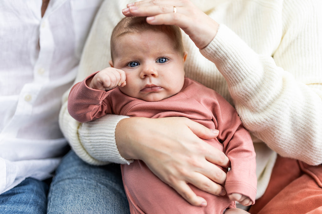 Mother holds newborn baby girl who wears sustainable long-sleeved baby onesie kimono