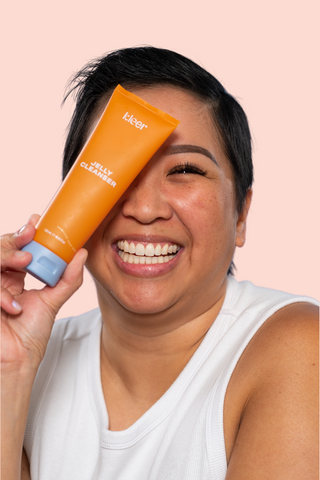 A women smiling with Kleer Jelly cleanser bottle over one eye. Image is ment to convey inclusivity