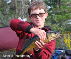 Kid holding a fish on a canoe trip