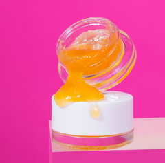 An OozeX 3g baller bucket of concentrate is slightly tipped sitting on top of the lid, pouring the wax onto the lid