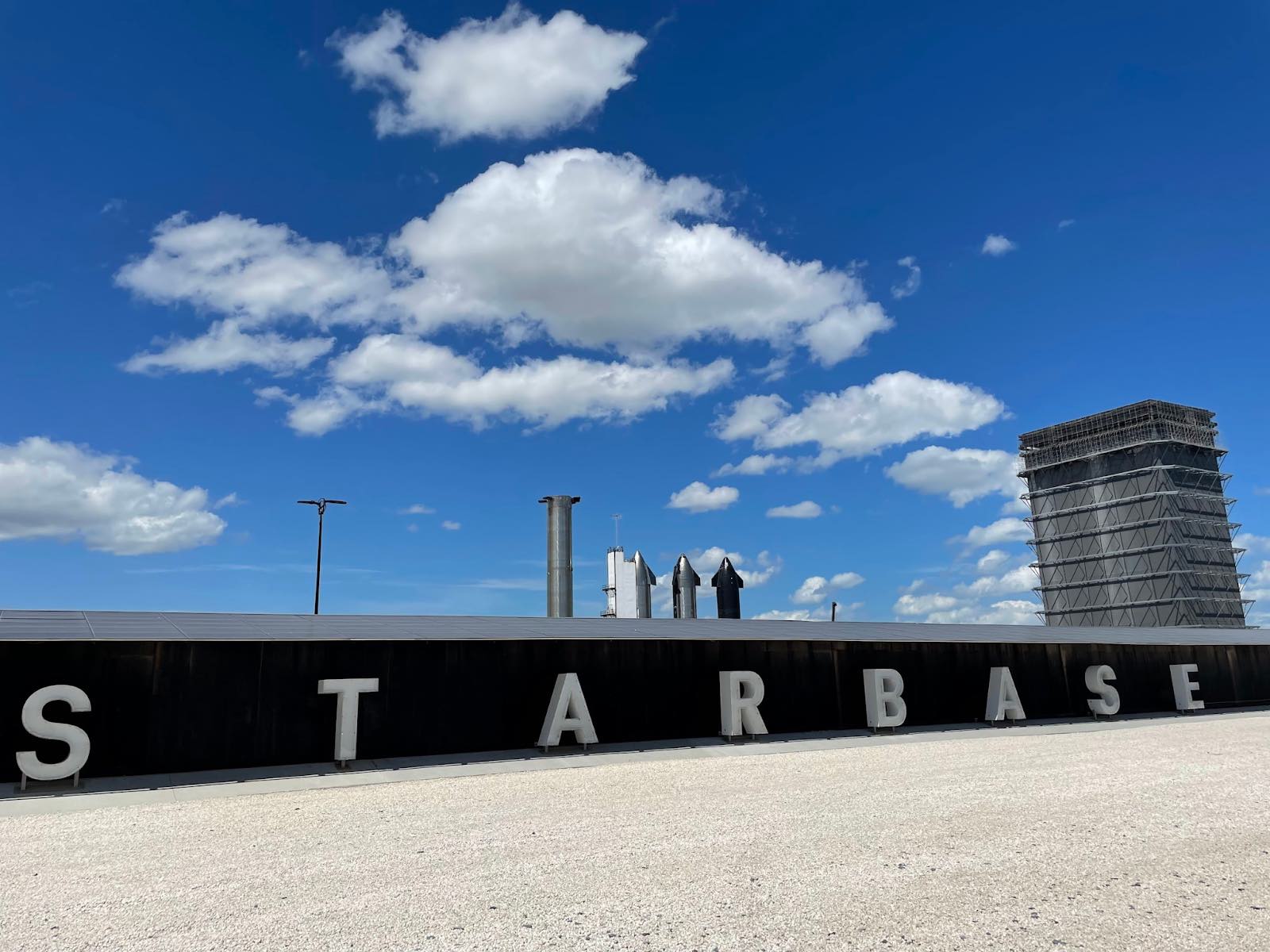 The official "Starbase" sign near SpaceX's Sanchez site with rockets visible in the background.