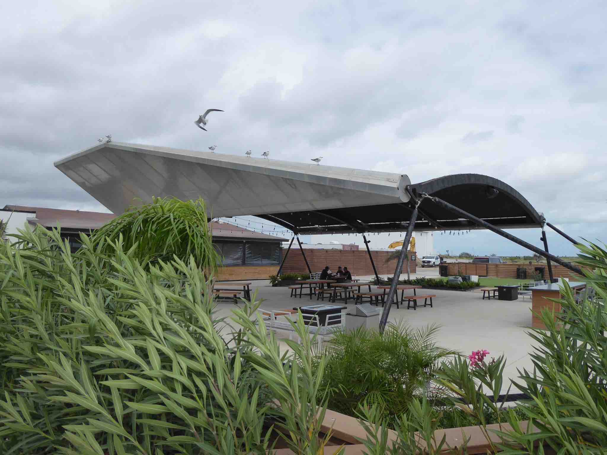 An outdoor photo showing the Astropub with Starship flap decorations and lots of lush grasses and plants.