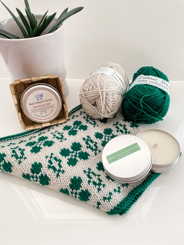 The Lucky Cowl Kit, including Debbie Bliss Cashmerino, The Blue Ewe stitch keeper cords, and a candle tin