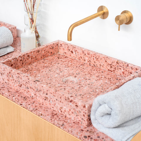 Roze terrazzo badkamermeubel samen met een gouden kraan van Furnified.ALT