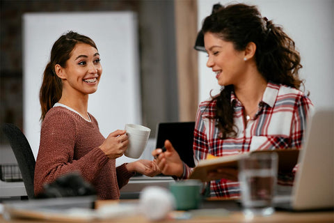 Zwei Frauen bei einem Gespräch am Arbeitsplatz.