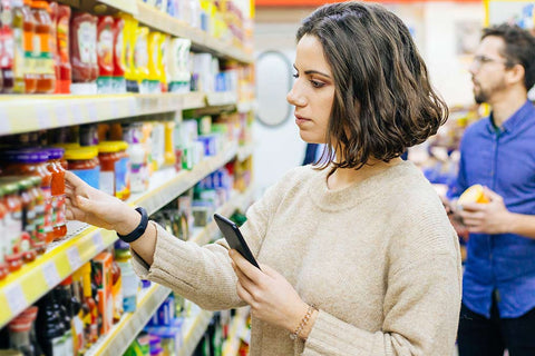 Eine junge Frau beim Einkaufen vor einem Supermarkt-Regal.