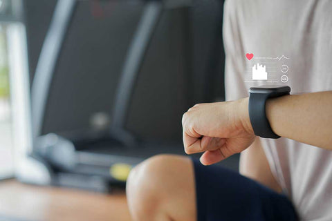 Ein Sportler kontrolliert im Fitnessstudio seinen Puls mit einer Smartwatch.