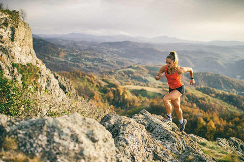 Eine Frau in einer Berglandschaft beim Laufen.