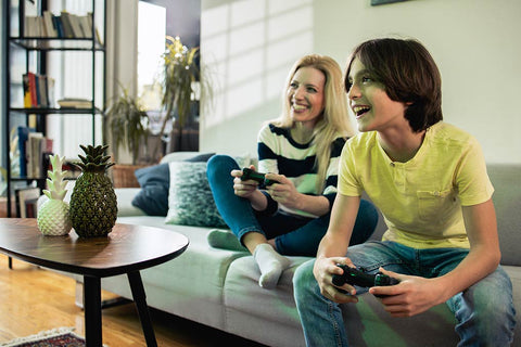 Eine Mutter sitzt mit ihrem jungen Sohn auf der Couch. Sie spielen gemeinsam ein Videospiel.
