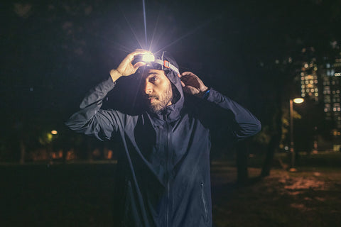 Ein Mann zieht zum Laufen bei Nacht eine Stirnlampe an.