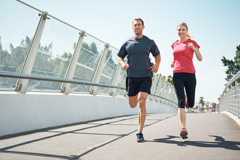 Ein Mann und eine Frau laufen in Sportbekleidung über eine Brücke.