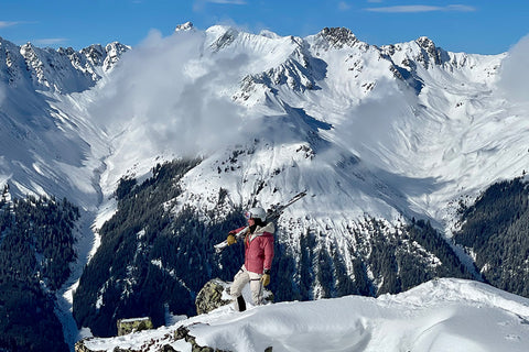 Eine Frau in Skiausrüstung vor einem beeindruckenden Bergpanorama.