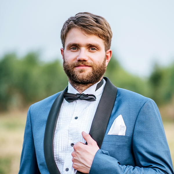 A man with a laid-back beard dressed for the wedding.