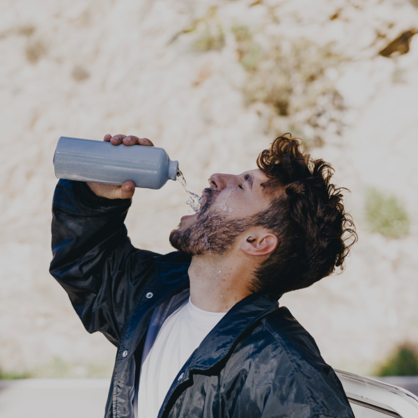 A man with beard drinking water from a bottle