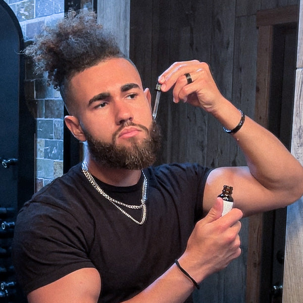 A man with beard applying a beard oil
