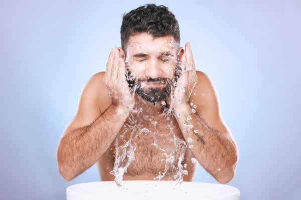 man washing his beard with cold water after swimming in a pool