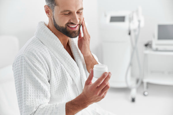 man applying moisturizer on his beard and face