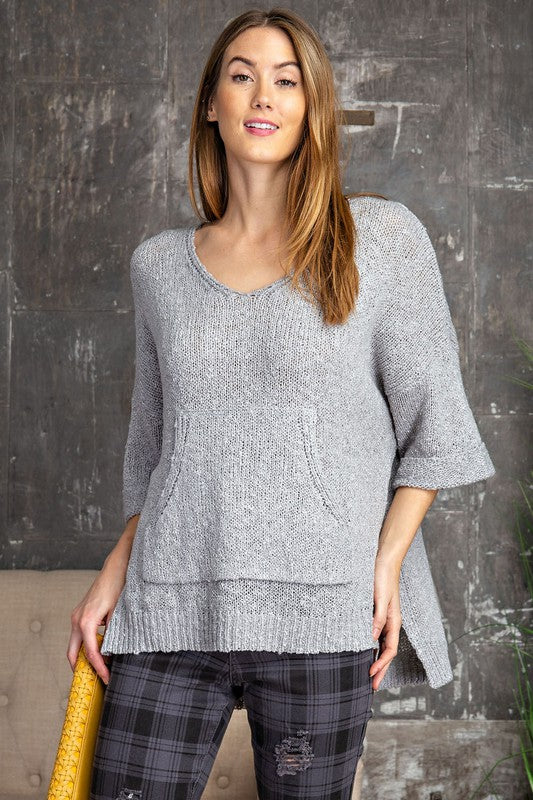 picture of woman wearing grey over size sweater with 3/4 sleeve and front kangaroo pocket