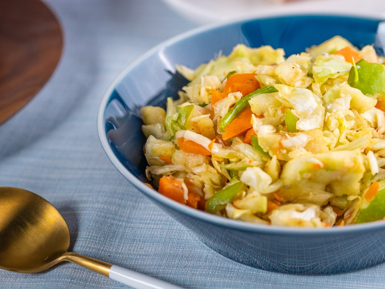 Chili Slaw in a blue bowl with gold utensil