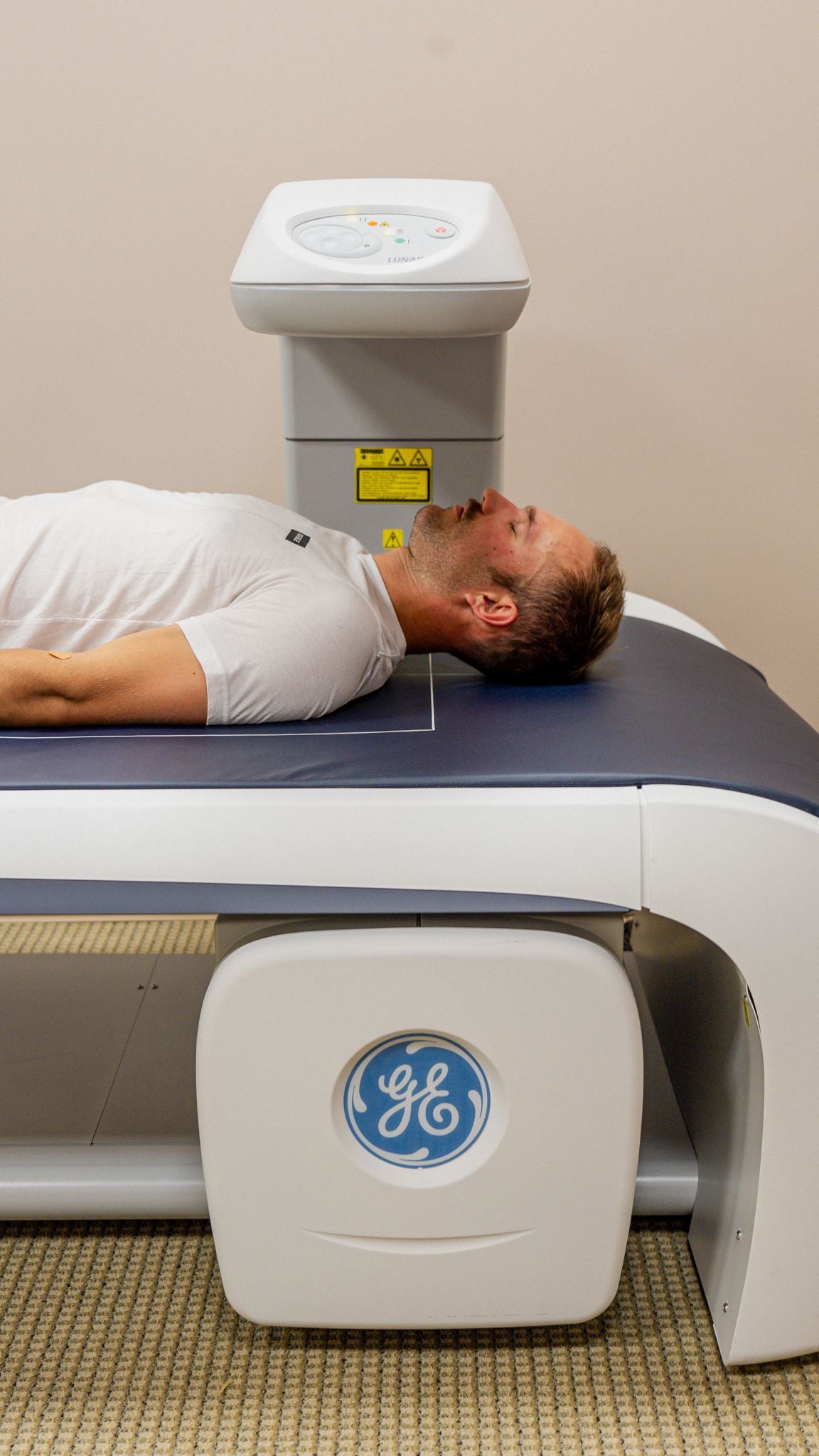 A man lying on a General Electric medical imaging machine.