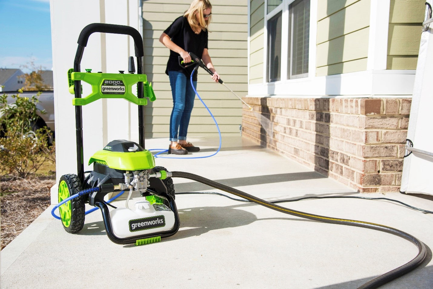 woman using a pressure washer on her front porch