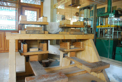 Manual wooden press, electric machine press in background
