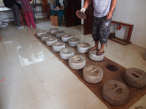 Steamed tea is pressed under a stone weight