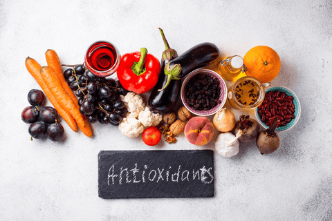 Das Wort Antioxidans auf grauem Schiefer & Gemüse