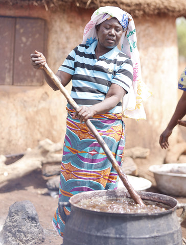 image of a woman carefully stirring as she produces shea butter