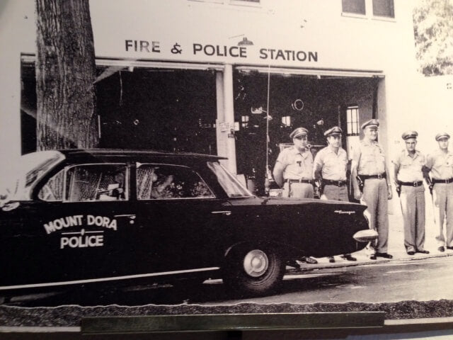 The building that is now home to Barrel of Books and Games in Mount Dora used to serve as the city's police and fire station. Five officers stand in front of the building next to a car with "Mount Dora Police" on the driver-side door.