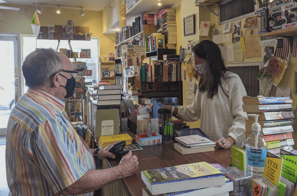 Barrel of Books and Games owner Crissy Stile accepts trade in books from a customer at the checkout counter.
