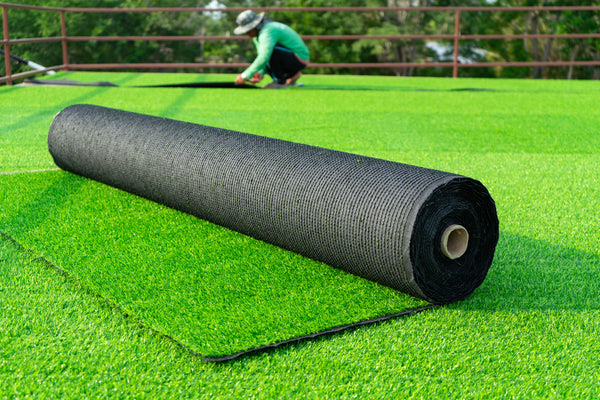 roll of astroturf or field turf matting of artificial grass soccer field,green lawn background with workers pave the counterfeit grass