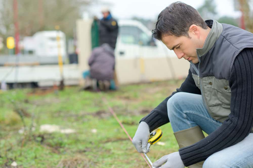 A builder taking measurements in the garden