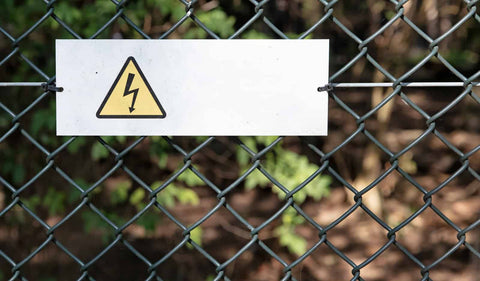 An electric fence with a yellow danger sign