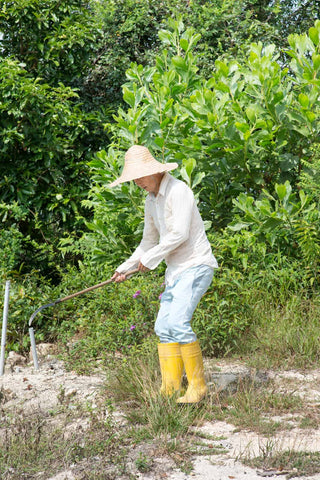 a middle-aged man wearing yellow boots and clearing the bushes