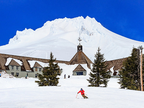 The exsterior of Timberline Lodge at the top of Mt. Hood in the Oregon with a skier in front of it.