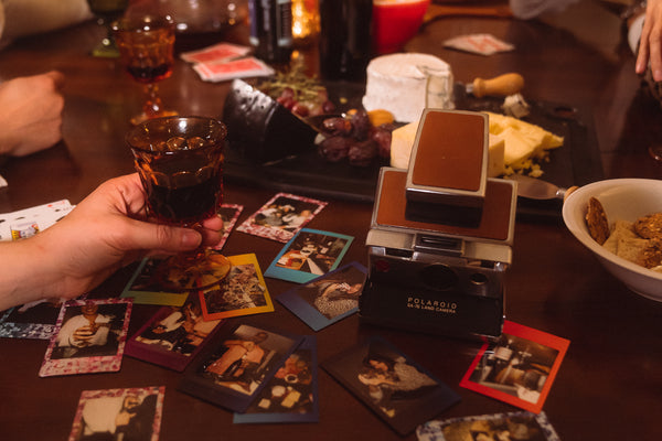 Polaroid pictures and glasses of wine spread out on a table.