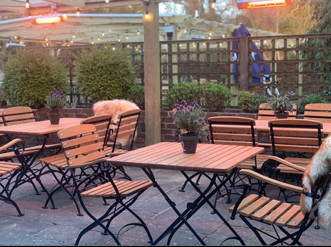 The smoking area of a pub with wooden furniture and multiple KMH-20 2KW Infrared Outdoor Wall Mounted Garden Heaters attached.