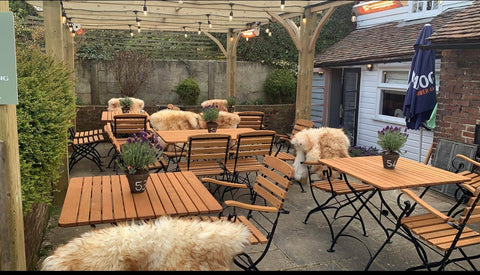 The outside area of a pub with wooden seating and multiple KMH-20 2KW Infrared Outdoor Wall Mounted Garden Heaters attached around the exterior to provide warmth.