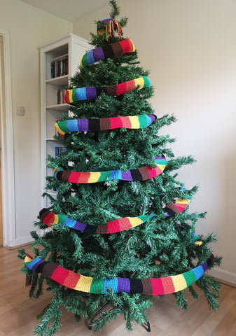 A Christmas tree festooned with a Philadelphia Rainbow in black, brown, red, orange, yellow, green, blue and purple.