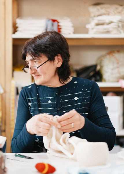 artisan looking to her right while working on a knitted white product