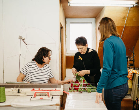 Three women working together and looking at their crochet project