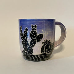 Mug with a cactus silhouette in front of a pink to purple and blue sunset sky.