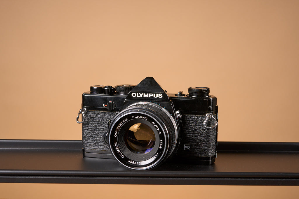 olympus om-1 camera on a light brown background