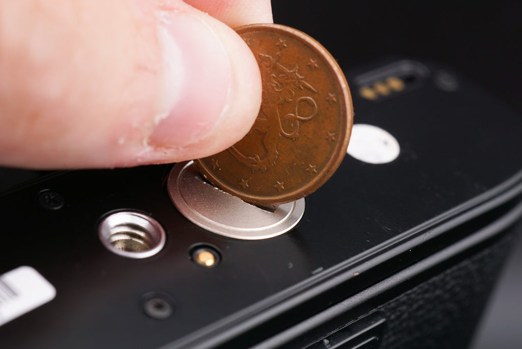 opening a Minolta X-700 battery cover with a coin