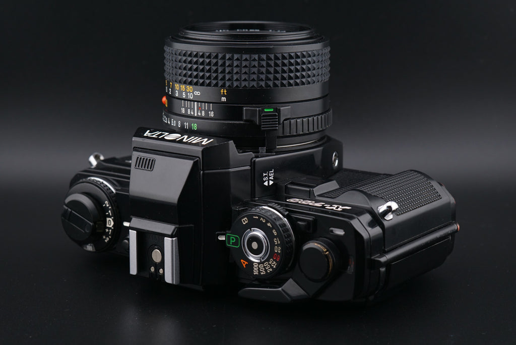 Minolta X-700 film camera laying on its back on a black background